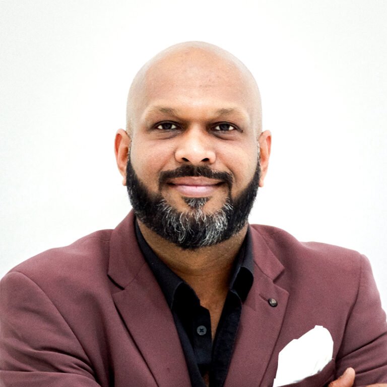 Bald man with a beard in a maroon blazer against a white background
