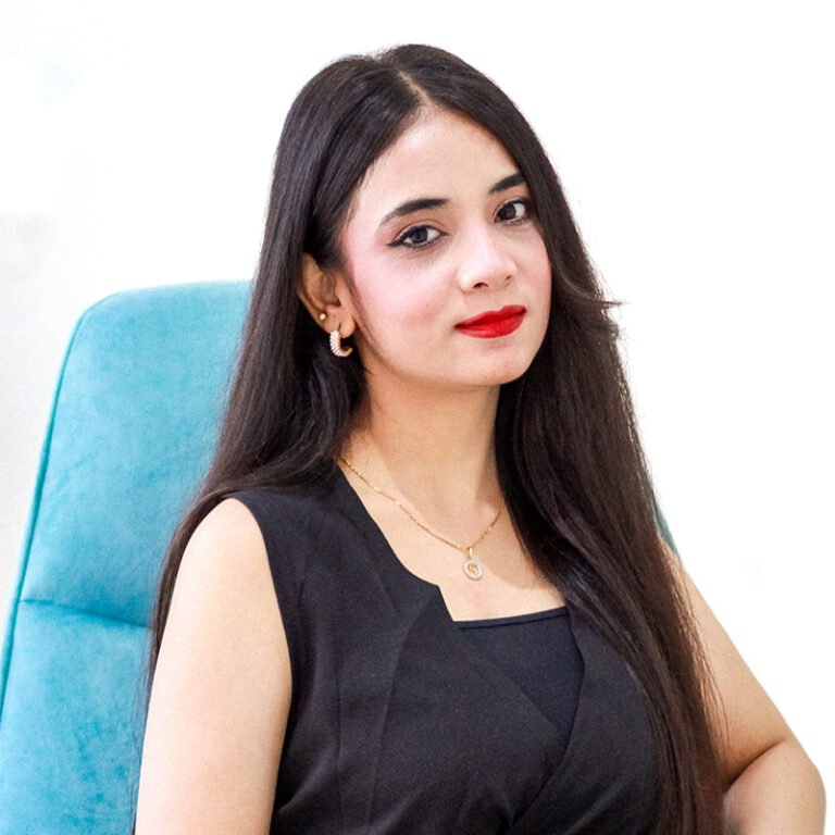 Portrait of a team member in a black top seated in a teal chair
